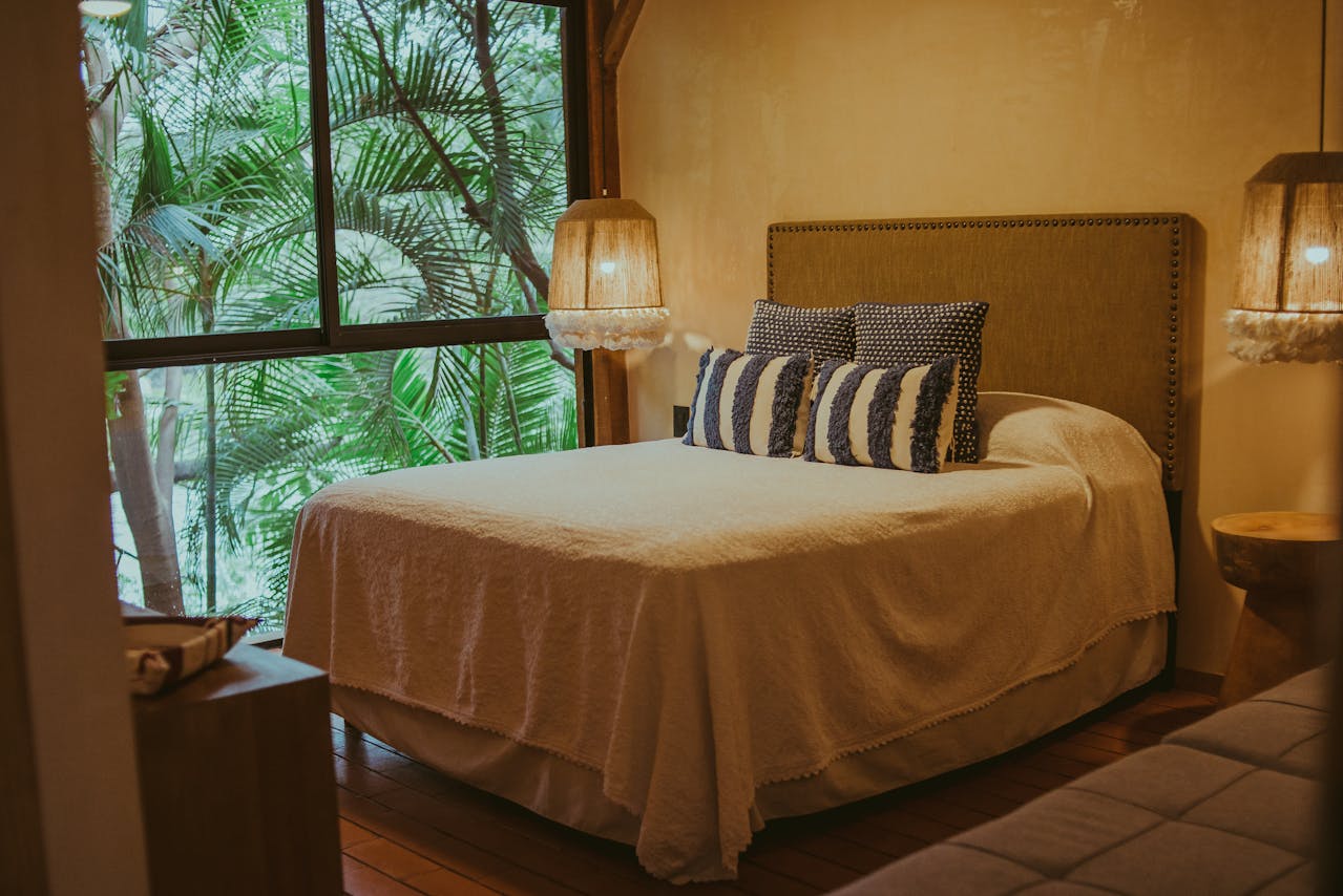 bedroom warm tone covers on bed palm trees outside